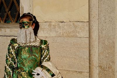 Portrait of mature woman standing on costume against wall during venice carnival