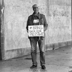 Full length portrait of man standing against wall