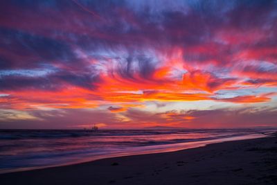 Scenic view of sea against dramatic sky during sunset