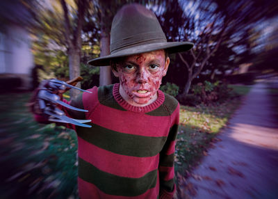 Portrait of serious boy dressed as murderer on street during halloween