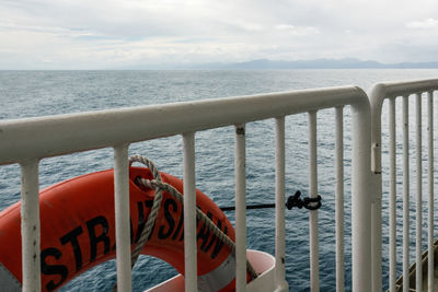 Railing of ferry by sea against sky