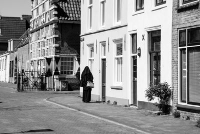 Rear view of woman walking on street against buildings in city