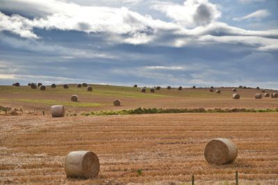 Hay bales on field against sky