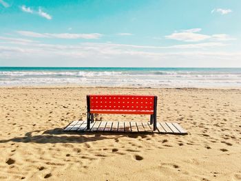 Chair on beach against sky