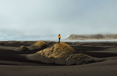 Man standing on beach against sky during winter