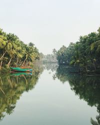 Boat moored on lake amidst trees against sky