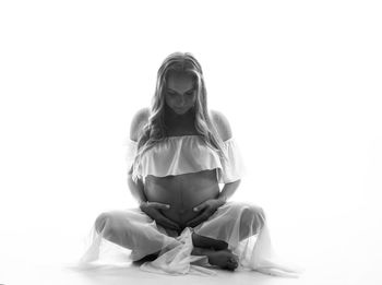 Portrait of woman sitting against white background