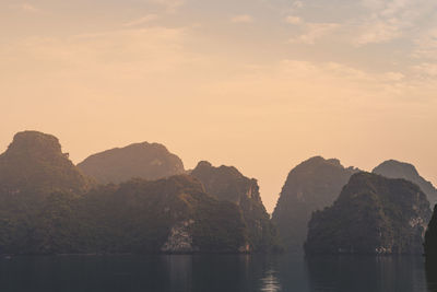 Rocks by sea against sky during sunset