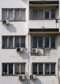 Weathered concrete building with multiple air conditioning units on the outside