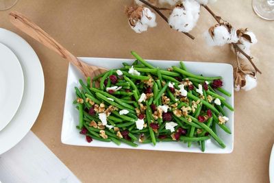 High angle view of green beans with walnuts and cheese served on table