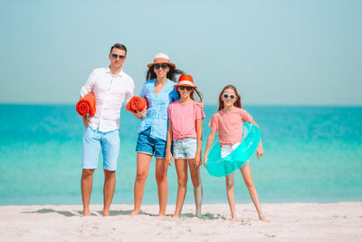 Portrait of family standing on beach against sea
