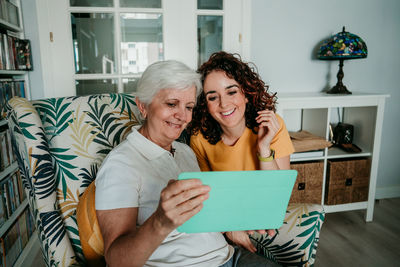 Smiling mother watching video with daughter over digital tablet at home