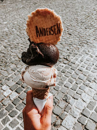 Close-up of hand holding ice cream cone on street