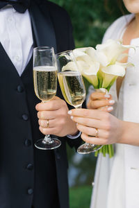 Newlyweds are holding glasses of champagne in their hands