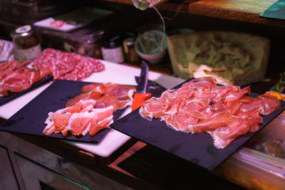 Slices of sliced raw ham arranged on black-colored cutting boards.