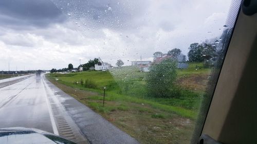 Road seen through wet glass window in rainy season