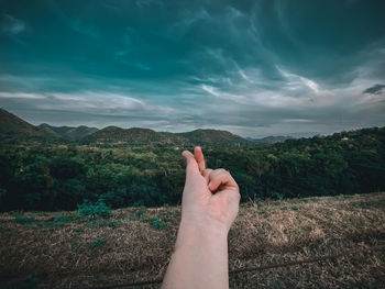 Midsection of person hand on mountain against sky