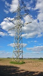 Low angle view of electricity pylon on field against sky
