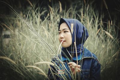 Portrait of young woman standing amidst plants