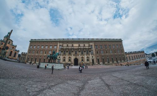 Tourists at town square against cloudy sky