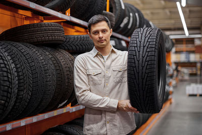 Portrait of man holding tire at store