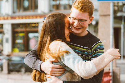 Young couple embracing while standing outdoors