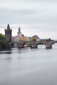 Arch bridge over river against buildings in city