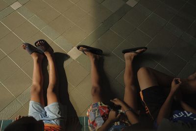 Low section of friends sitting on tiled floor