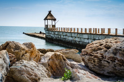 Lifeguard hut on rocks by sea against sky