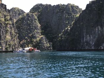 Boats sailing in sea against mountains