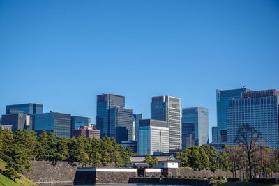 Buildings in city against clear blue sky