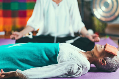 Close-up of mature woman relaxing while yoga instructor meditating at spa