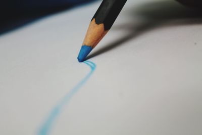 Close-up of blue colored pencil on paper