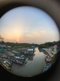 Boats moored in river against sky during sunset