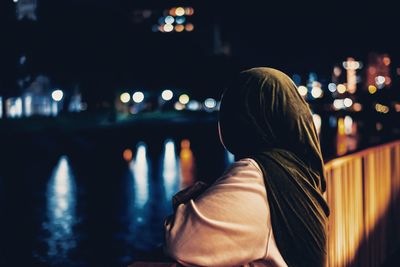 Rear view of woman in illuminated city at night