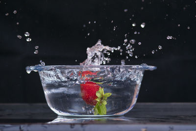 Close-up of water splashing in glass against black background