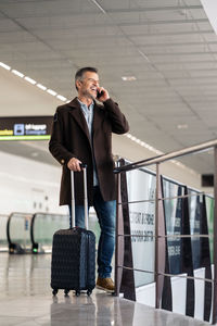 Full length of man using mobile phone in airport