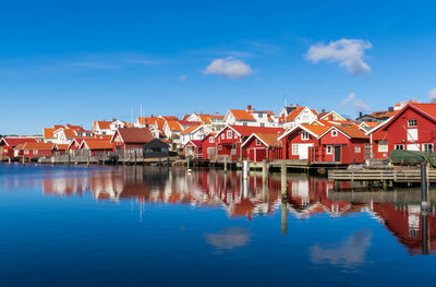 Buildings by lake against blue sky