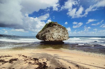 Rocks on beach by sea against sky