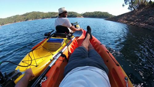 Rear view of men on boat sailing in lake against clear sky