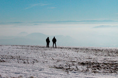 People on snow covered land against sky