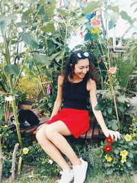 Portrait of smiling young woman sitting on grass against trees