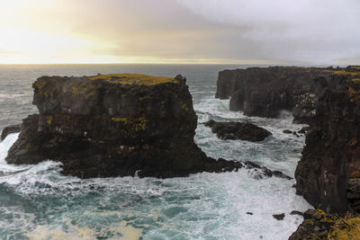 Rock formations by sea against sky