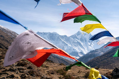 Multi colored flags hanging on mountain against sky