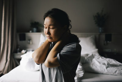Young woman looking away while lying on bed at home