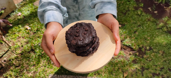 Midsection of person holding ice cream on field