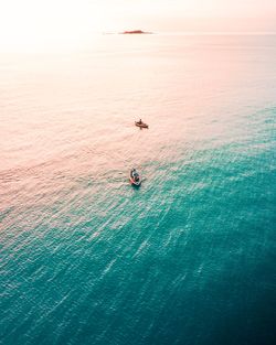 High angle view of people in canoes on sea during sunset