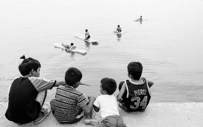 Rear view of people sitting on beach