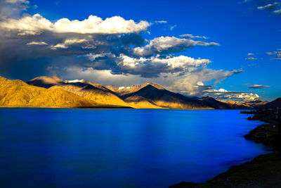 Scenic view of lake and mountains against blue sky