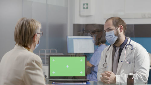 Male doctor discussing with senior woman at hospital